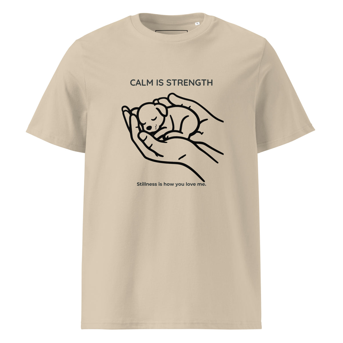 A beige short-sleeve crewneck t-shirt featuring a black line art graphic of a sleeping puppy nestled in human hands, with the text 'CALM IS STRENGTH' above and 'Stillness is how you love me.' below.